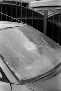 A monochrome image of a car with a broken windshield, emphasizing damage and texture.